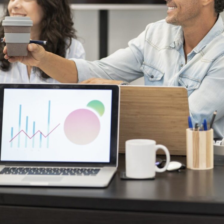 Teambesprechung mit Laptop und Grafik im Vordergrund